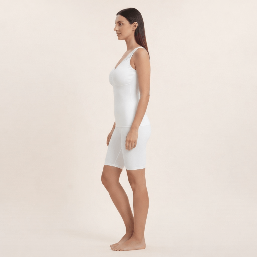 Caraco gainant blanc avec dentelle aux épaules et short cycliste blanc, vue de profil, studio ivoire crème.