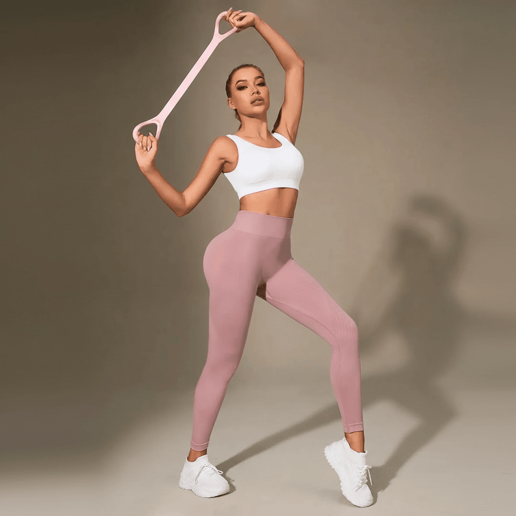 Legging anti cellulite femme rose poudré avec pose sportive et bras levés en studio beige minimaliste