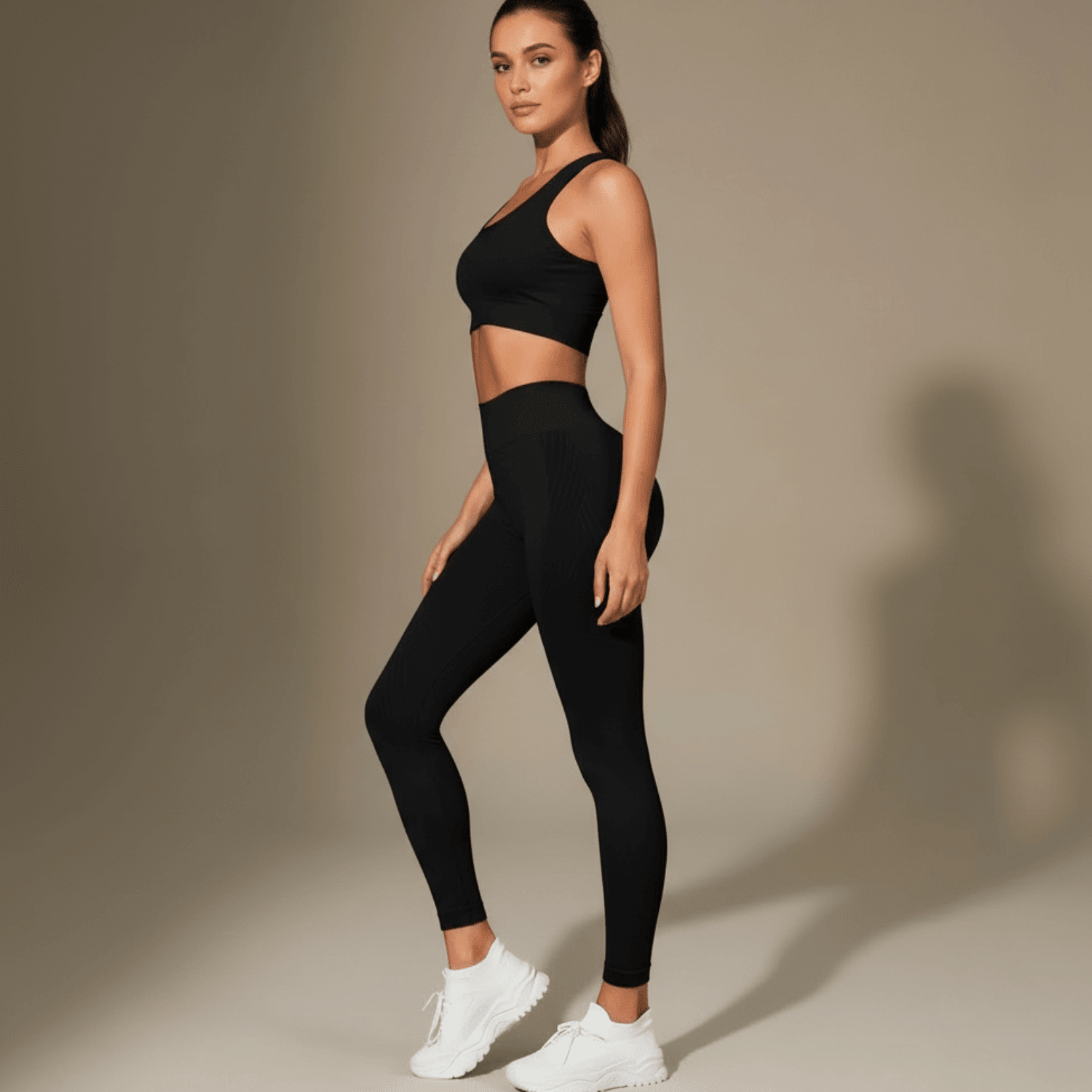 legging anti-cellulite noir vue de profil en pose élégante avec taille haute côtelée et matière lisse brillante en studio minimaliste beige