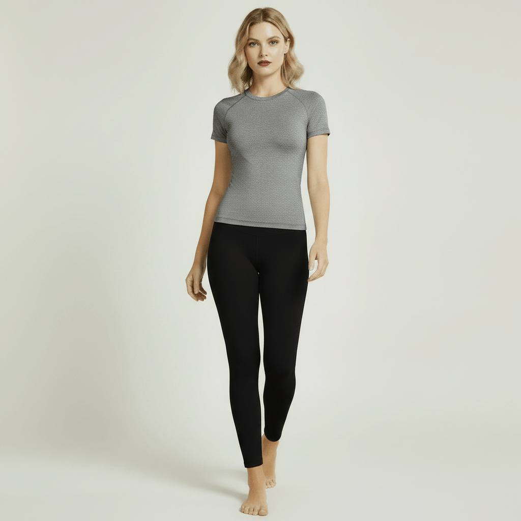 T-shirt Anti-UV Femme gris chiné slim fit, pose marche neutre sur femme blonde, legging noir, studio ivoire minimaliste
